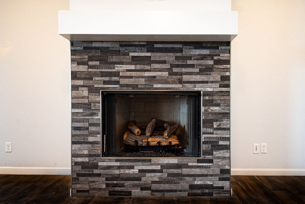 A gray fireplace with unlit firewood inside on a white background of living room wall