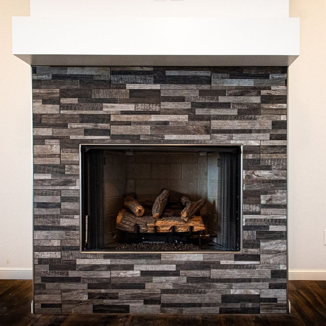 A gray fireplace with unlit firewood inside on a white background of living room wall